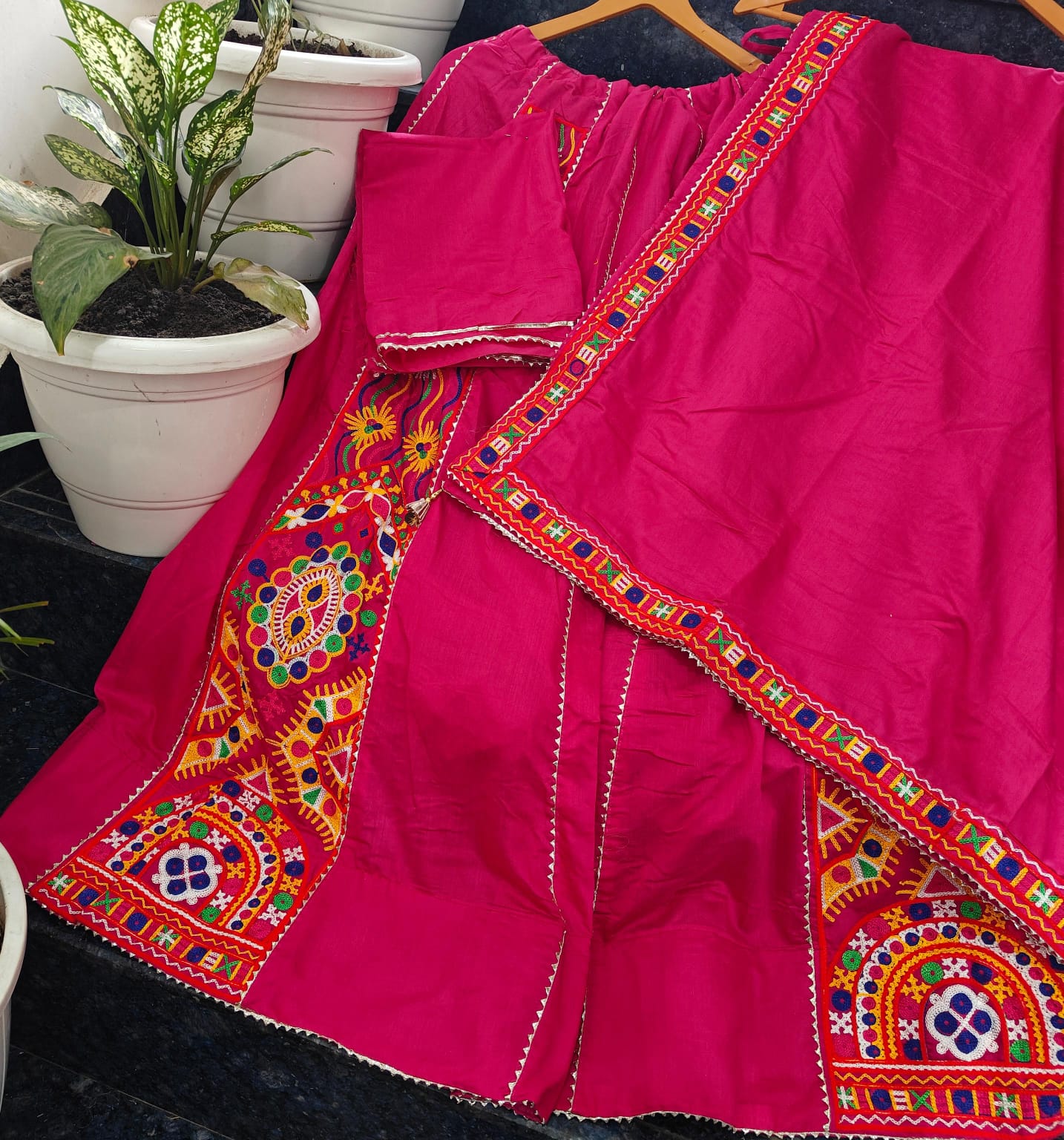 Pink traditional outfit with colorful embroidery on a dark surface.