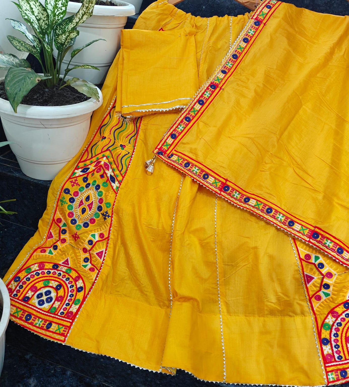 Yellow traditional outfit with colorful embroidery on a dark surface.