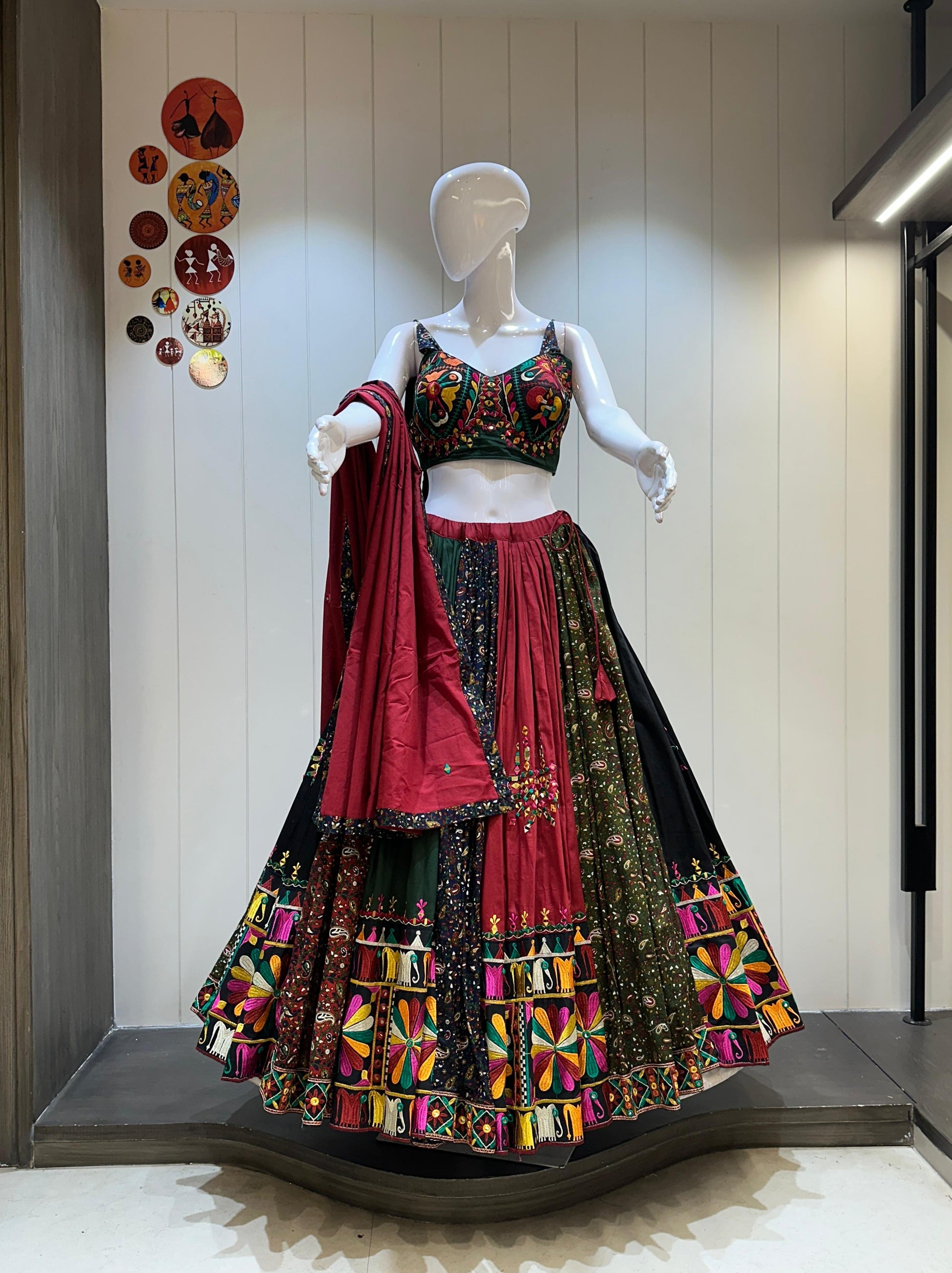 Mannequin wearing a colorful traditional outfit with a red dupatta against a neutral background