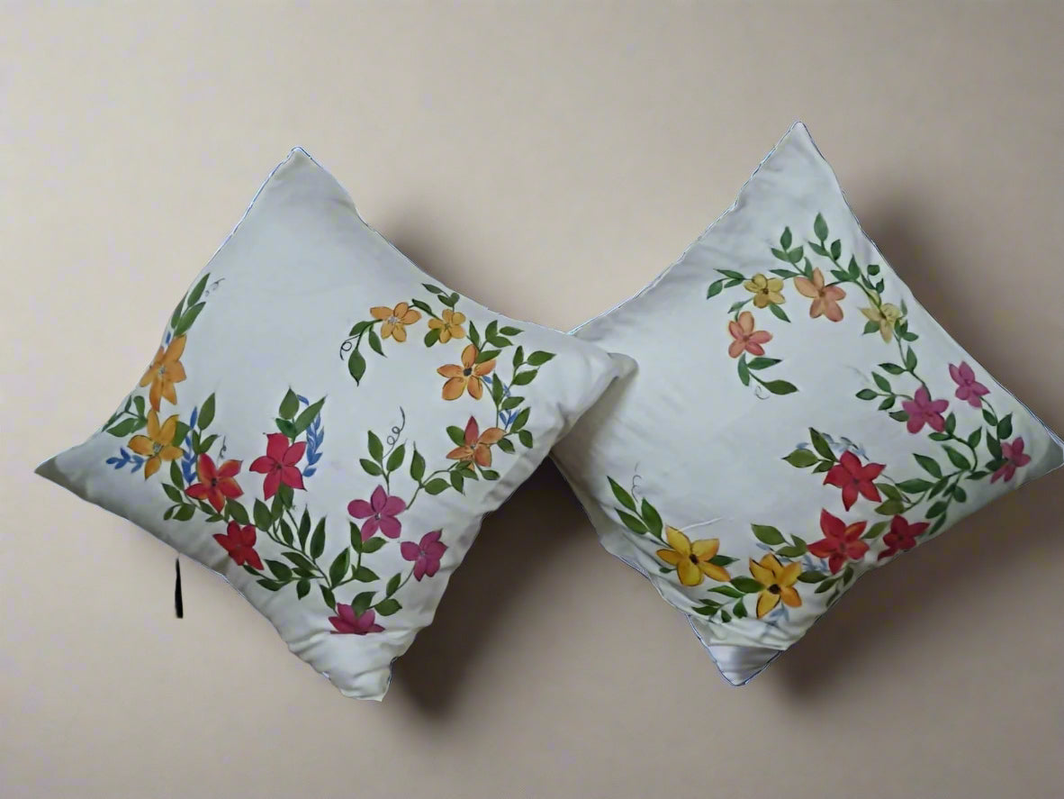 Two floral embroidered pillows on a chair with a blurred background of a room.